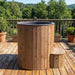 Wooden hot tub on a wooden deck with a scenic background